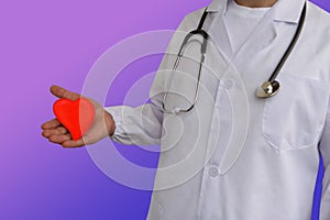 Photo of a doctor with a stethoscope with a heart in his hand on a purple background, concept of healthcare, cardiological photo