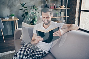 Photo of domestic homey handsome guy stay home quarantine time reader book worm good mood sit comfy cozy sofa modern