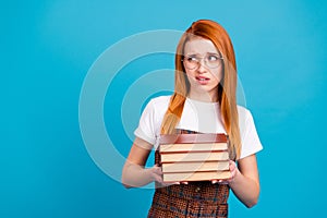 Photo of doubtful distrustful woman dressed checkered dress glasses holding stack book empty space isolated blue color
