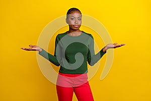 Photo of doubtful pretty young woman wear green shirt shrugging shoulders arms empty space isolated yellow color