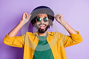 Photo of dreads hairstyle dark skin person hands touch cap open mouth smile isolated on violet color background