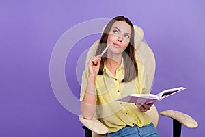 Photo of dream young brunette lady look empty space write sit on armchair wear top isolated on violet color background