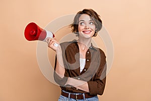 Photo of dreamy charming lady wear brown shirt holding loud speaker looking empty space isolated beige color background