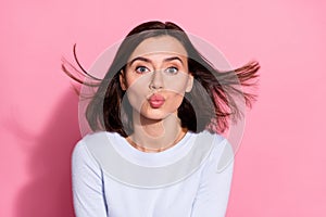 Photo of dreamy flirty young lady dressed white jumper wind blowing sending you kiss isolated pink color background