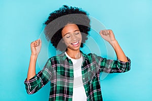 Photo of dreamy glad positive little lady raise fists anticipate victory wear plaid shirt isolated teal color background