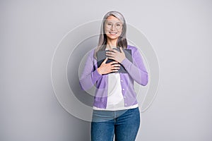 Photo of dreamy grandmother holding book with novels smiling wearing casual purple cardigan jeans eyewear isolated on