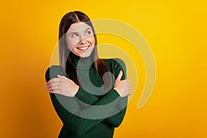 Photo of dreamy inspired lady hug herself look empty space dream wear green shirt isolated on yellow background