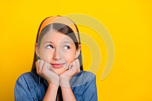 Photo of dreamy pretty student girl wear denim shirt smiling arms cheeks looking empty space isolated yellow color