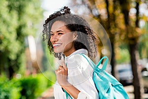 Photo of dreamy shiny lady wear white shirt rucksack walking university enjoying sunny weather outside urban city park