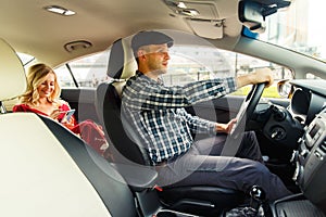 Photo of driver and blonde in back seat with phone in their hands sitting in taxi.