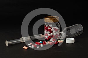 photo of drugs scattered outside their packaging next to syringes