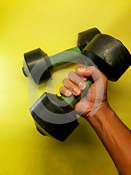 Photo of dumbbell hand muscle exercise equipment with a yellow background