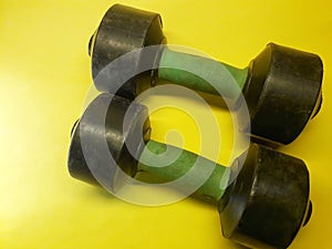 Photo of dumbbell hand muscle exercise equipment with a yellow background