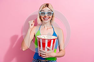 Photo of ecstatic girl with bob hairdo dressed colorful tank hold popcorn watch footbal in 3d glasses isolated on pink