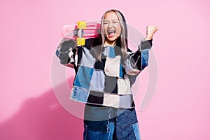 Photo of ecstatic girl dressed jeans pullover holding skateboard on hsoulder scream raising fist up isolated on pink