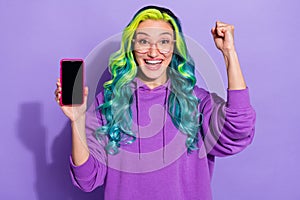 Photo of ecstatic lady with vivid hairdo hold smart phone fist up win low price offer lottery isolated over violet color