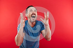 Photo of ecstatic man screaming and rejoicing with gesturing like winner or successful person, isolated over red background