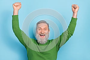Photo of ecstatic mature aged man raise hands up enjoy lucky aim goal win wear sweater isolated blue color background