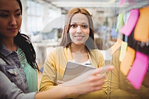 Photo editor standing near female coworkers pointing on sticky note