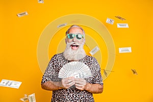 Photo of elderly old confident rich man holding banknotes in his hands and being rained with currency while isolated