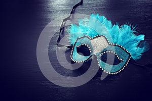 Photo of elegant and delicate blue Venetian mask over dark wooden background