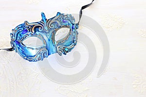 Photo of elegant and delicate blue Venetian mask over white wooden background