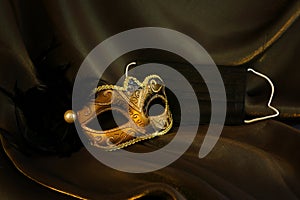 Photo of elegant and delicate gold Venetian mask over black silk background. Coronavirus prevention concept