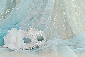 Photo of elegant and delicate Venetian mask over gold and blue chiffon background