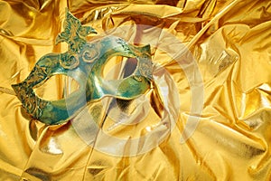 Photo of elegant and delicate Venetian mask over gold silk background