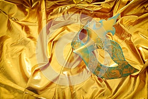 Photo of elegant and delicate Venetian mask over gold silk background