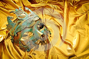 Photo of elegant and delicate Venetian mask over gold silk background