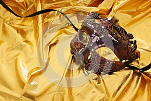 Photo of elegant and delicate Venetian mask over gold silk background