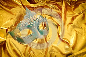 Photo of elegant and delicate Venetian mask over gold silk background