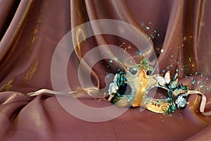 Photo of elegant and delicate Venetian mask over gold silk background