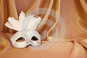 Photo of elegant and delicate Venetian mask over gold silk background
