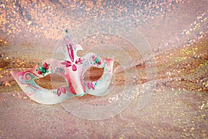 Photo of elegant and delicate Venetian mask over pink sequins chiffon sparkle background