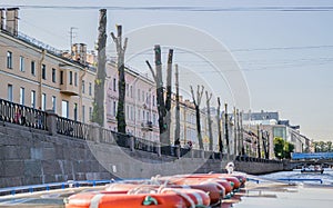 Photo embankment with floating pleasure boat. Trimmed trees on the embankment