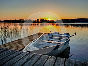 Photo of an empty boat at the pier in the lake at sunset