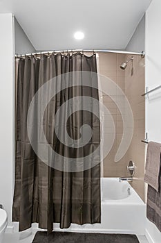 A photo of a empty shower with black curtain in a house