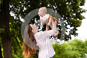 Photo of excited cheerful mother little son dressed casual clothes rising arms enjoying sunshine outdoors backyard