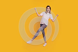 Photo of excited funny carefree lady dance have fun wear casual t-shirt jeans sneakers on yellow background