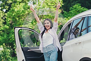 Photo of excited girl enjoy buying new private car rejoice make v-sign cant wait drive ride in town center outside