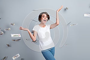 Photo of excited positive woman dressed white t-shirt catching falling money isolated grey color background