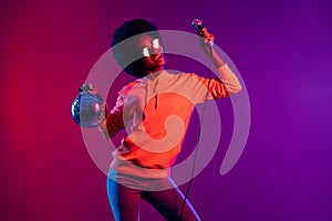 Photo of excited pretty lady hold microphone disco ball open mouth wear hoodie glasses isolated gradient neon background