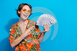 Photo of excited successful person toothy smile indicate finger hand hold dollar bills isolated on blue color background