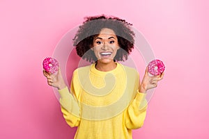 Photo of excited sweet woman dressed kitted pullover holding two donuts isolated pink color background