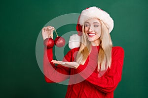 Photo of excited sweet young woman dressed knitted pullover holding arm decoration balls smiling isolated green color