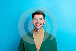 Photo of excited thoughtful man wear green cardigan spectacles looking up empty space isolated blue color background