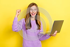 Photo of excited youngster crazy positive schoolgirl wear purple sweater hold new apple macbook fist up finally homework