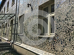 Photo of the exterior of a house covered with mirror mosaic. Facade with mirrors. Poland, Lodz, Piotrkowska Street.